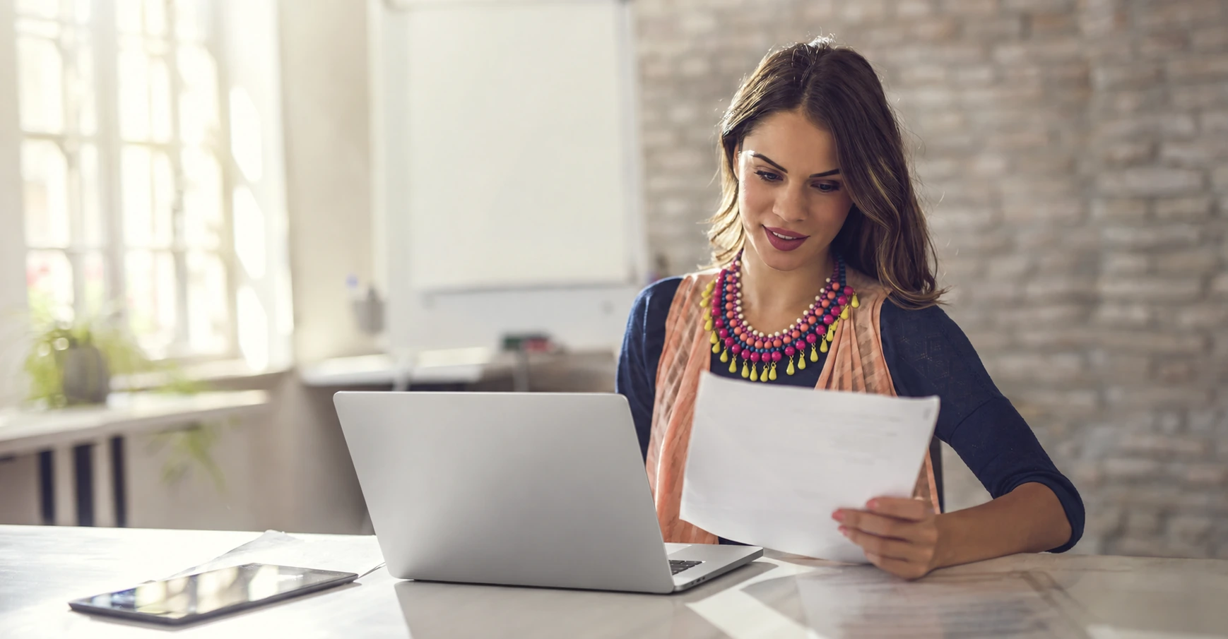 Professional executive assistant reviewing documents at her desk